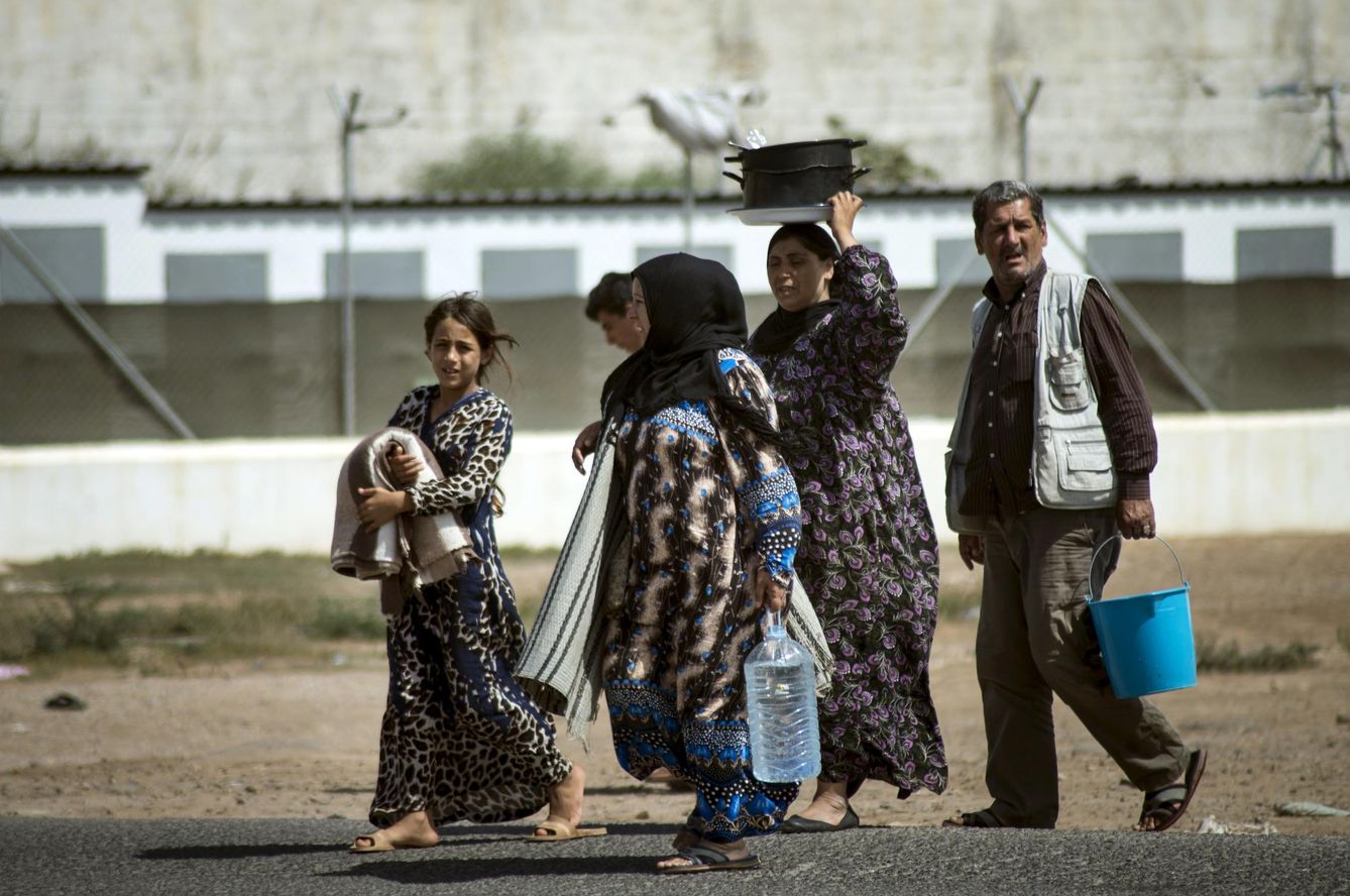 Una familia de refugiados sirios camina ante las puertas del CETI de Melilla. (Reuters)