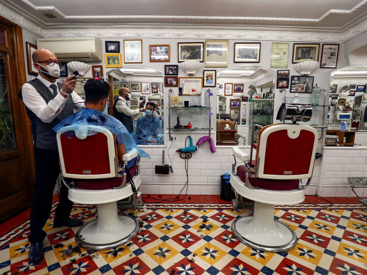Foto: Dos hombres en una peluquería en Madrid. (Reuters)