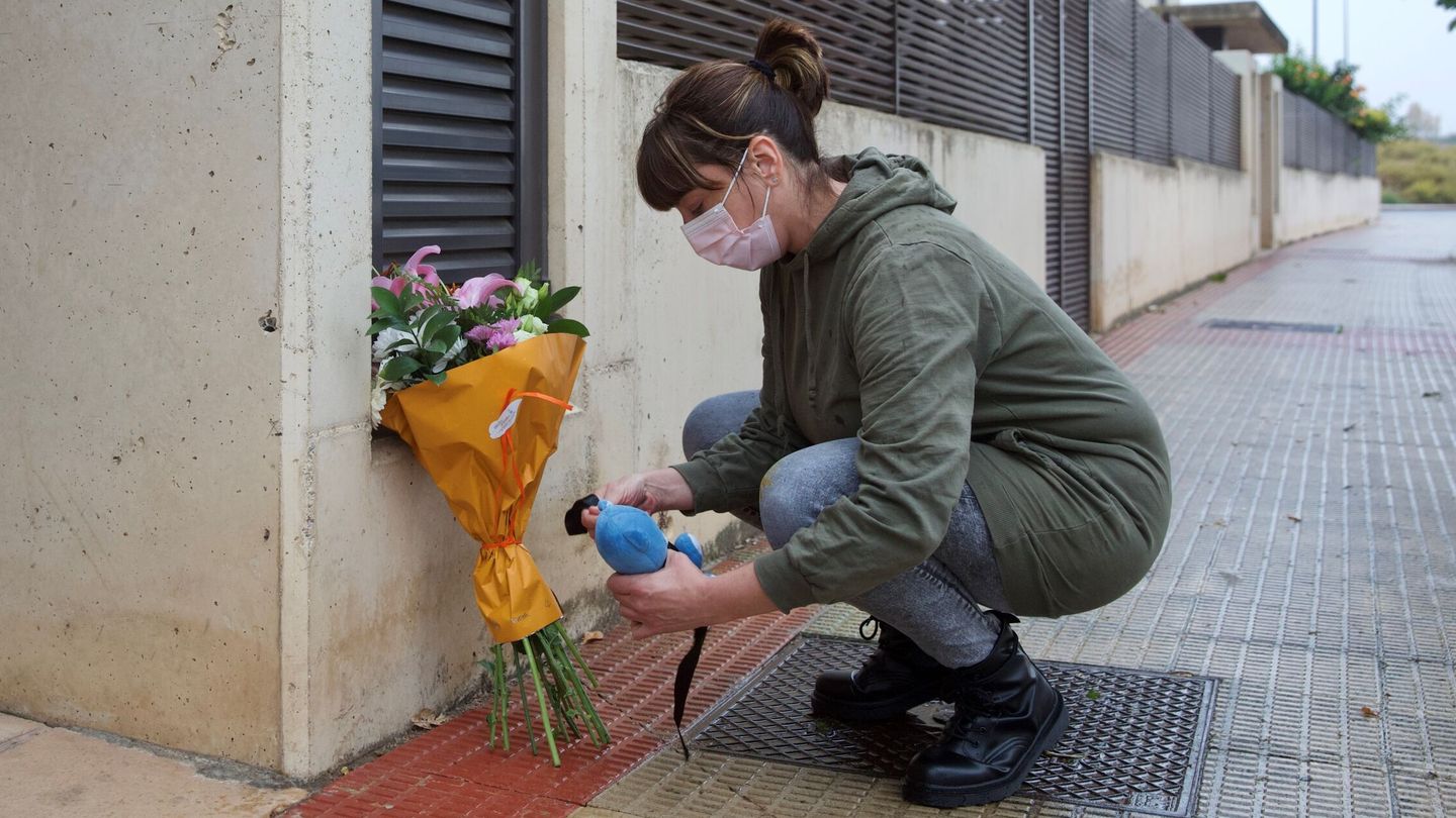 Una mujer coloca flores y un oso de peluche en el portal donde apareció el niño asesinado anoche en Lardero. (EFE)