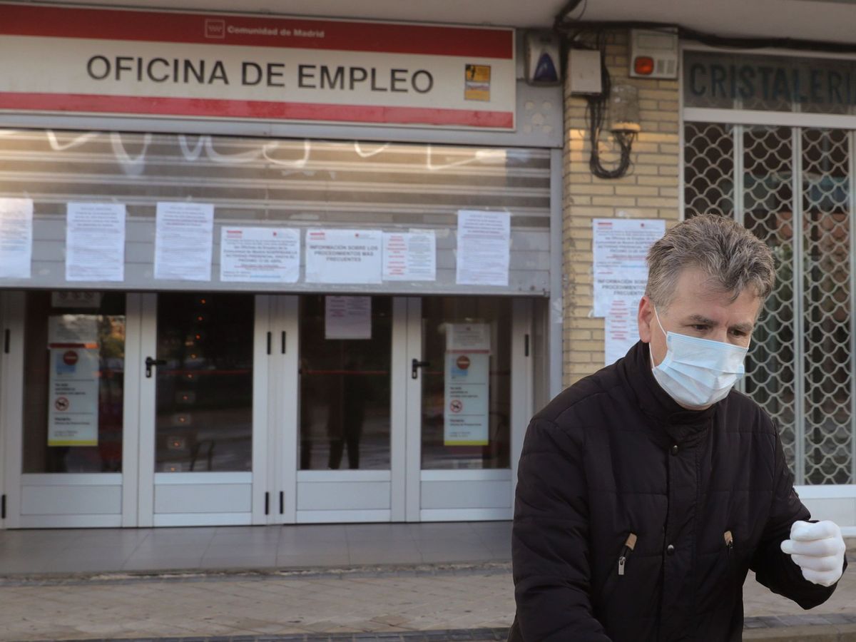 Foto: Un hombre con mascarilla y guantes pasa por delante de una oficina de empleo en Madrid (EFE)