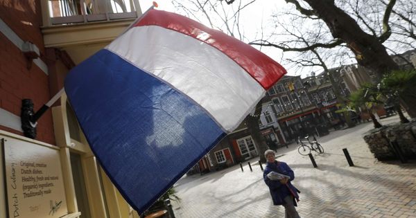 Foto: Una mujer pasa por debajo de una bandera holandesa el día antes de las elecciones en Delft, el 14 de marzo de 2017. (Reuters)