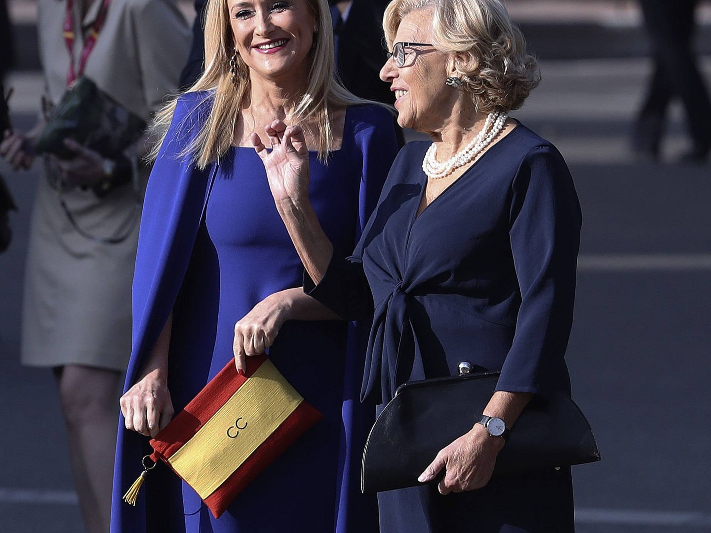 Cristina Cifuentes charla con Manuela Carmena mientras presume de bolso con la bandera de España. (EFE)