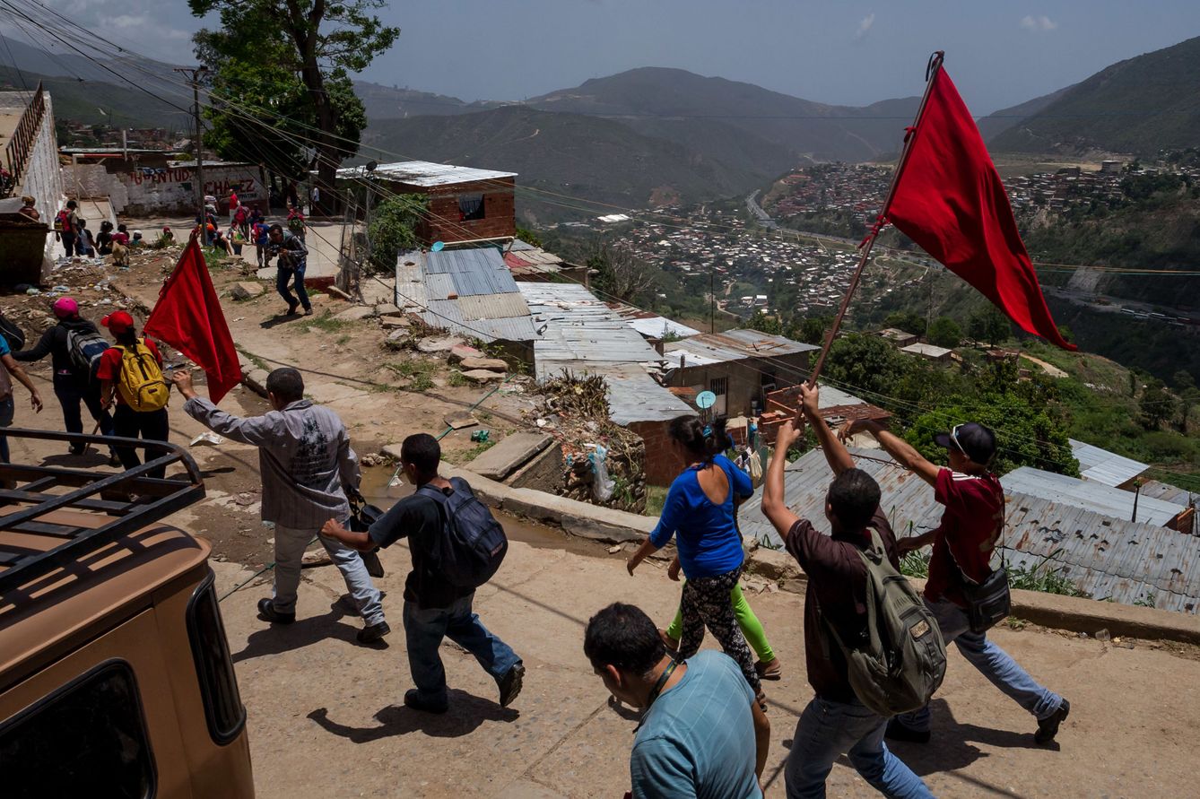 Miembros de la Fuerza Armada Nacional Bolivariana (FANB) y civiles ondean banderas rojas durante unos ejercicios militares en un barrio al oeste de Caracas, el 20 de mayo de 2016. (EFE)