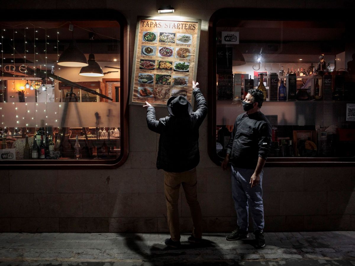 Foto: Unos trabajadores de un restaurante del centro de València recogen la terraza. (EFE)