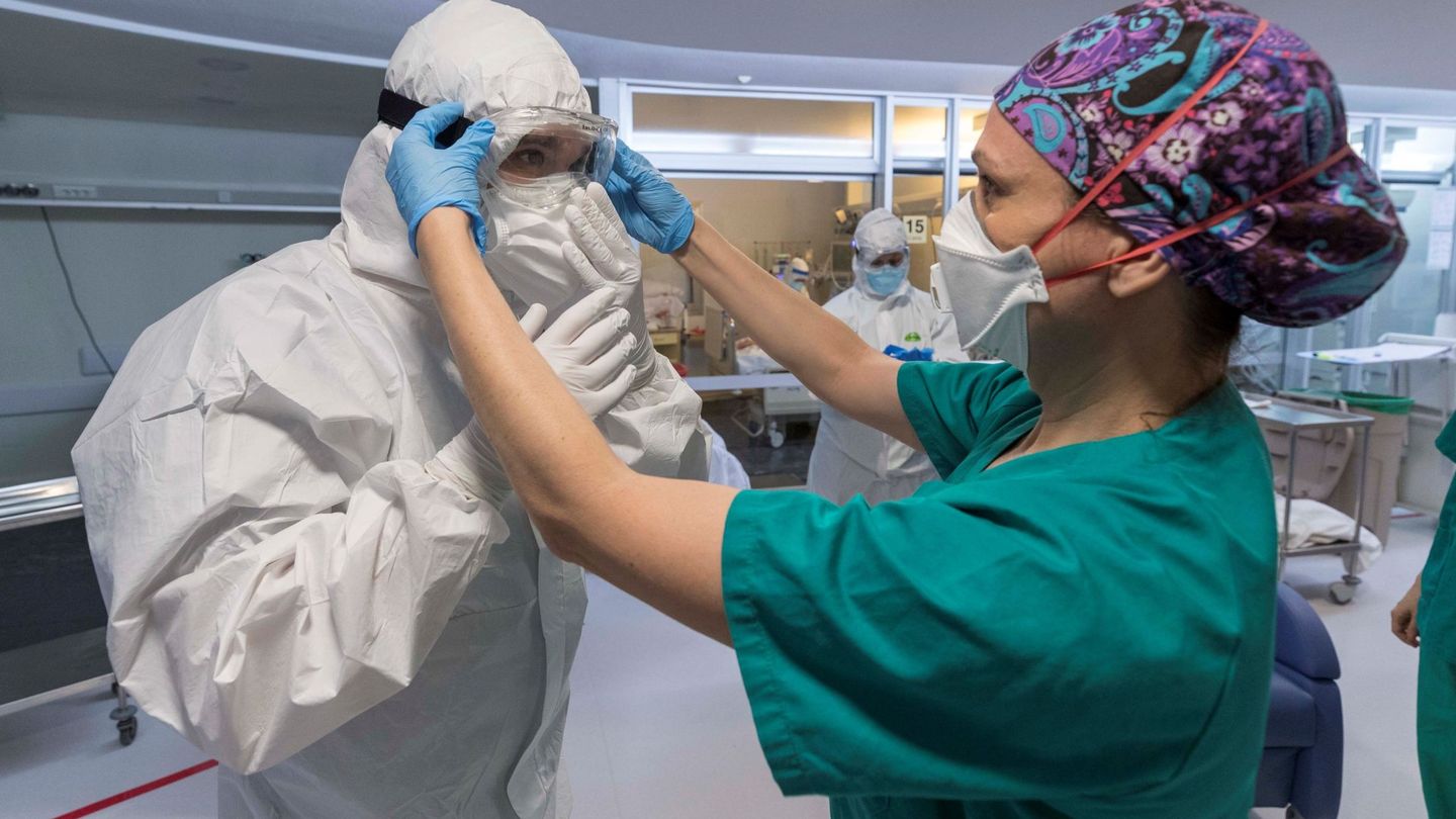 Una enfermera de la unidad de cuidados intensivos (UCI), ayuda a un compañeros a colocarse las protecciones necesarias antes de entrar en un box para atender a un paciente infectado con COVID 19, en el hospital universitario Morales Meseguer de Murcia. (EFE)