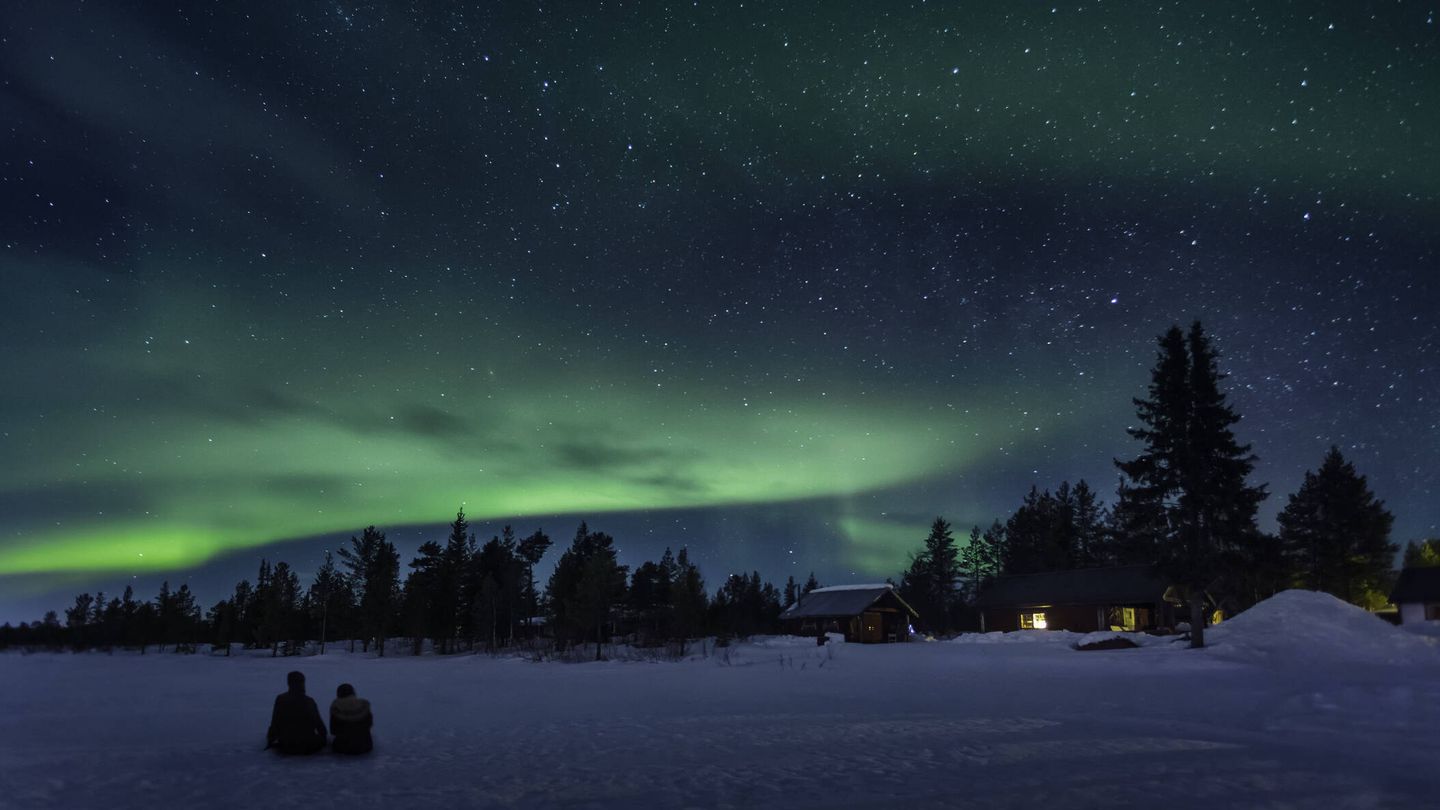 Dos personas ven la aurora al norte de Suecia.