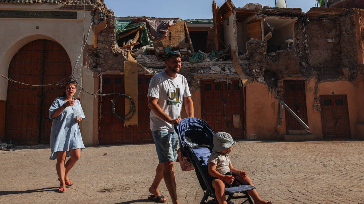 Dos turistas pasean en el centro de la medina de Marrakech. Al fondo, el fuerte seísmo del pasado 8 de septiembre deja entrever restos personales. (Francisco Sarrio Volpi)