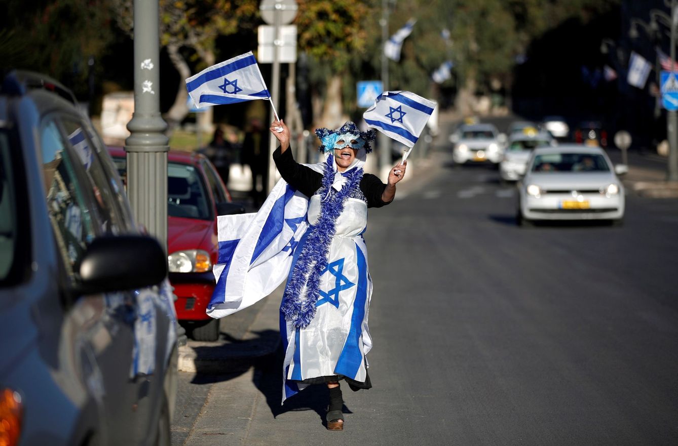 Una mujer cubierta de banderas israelíes baila por las calles de Jerusalén. EFE