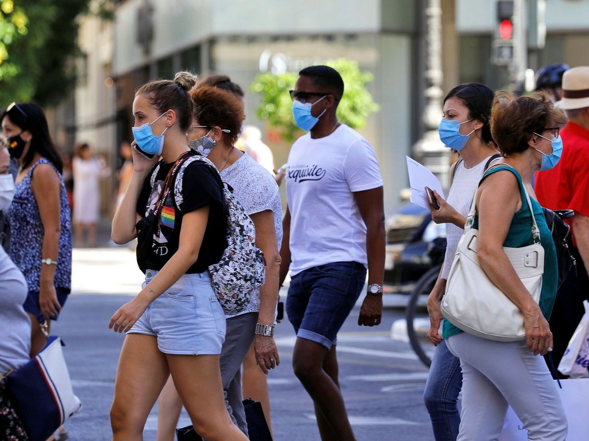 Foto: Varias personas, todas ellas con mascarilla, cruzan un paso de peatones en una calle de Valencia. (EFE)