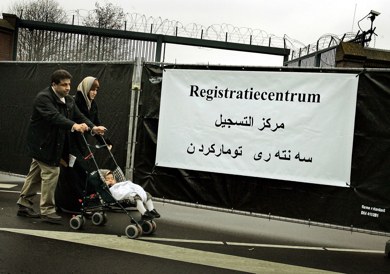 Una familia iraquí pasa ante un cartel donde pone 'Centro de registro' en una base naval de Ámsterdam. (Reuters)
