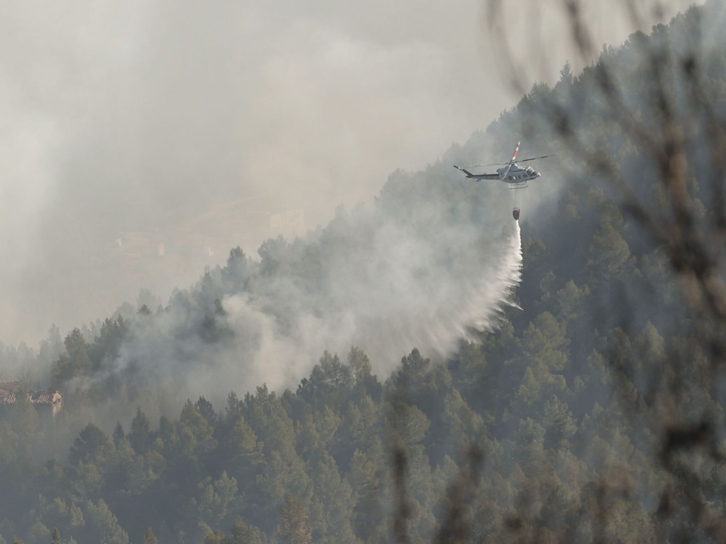 Un helicóptero trabaja en la extinción del incendio. (EFE/Manuel Bruque)