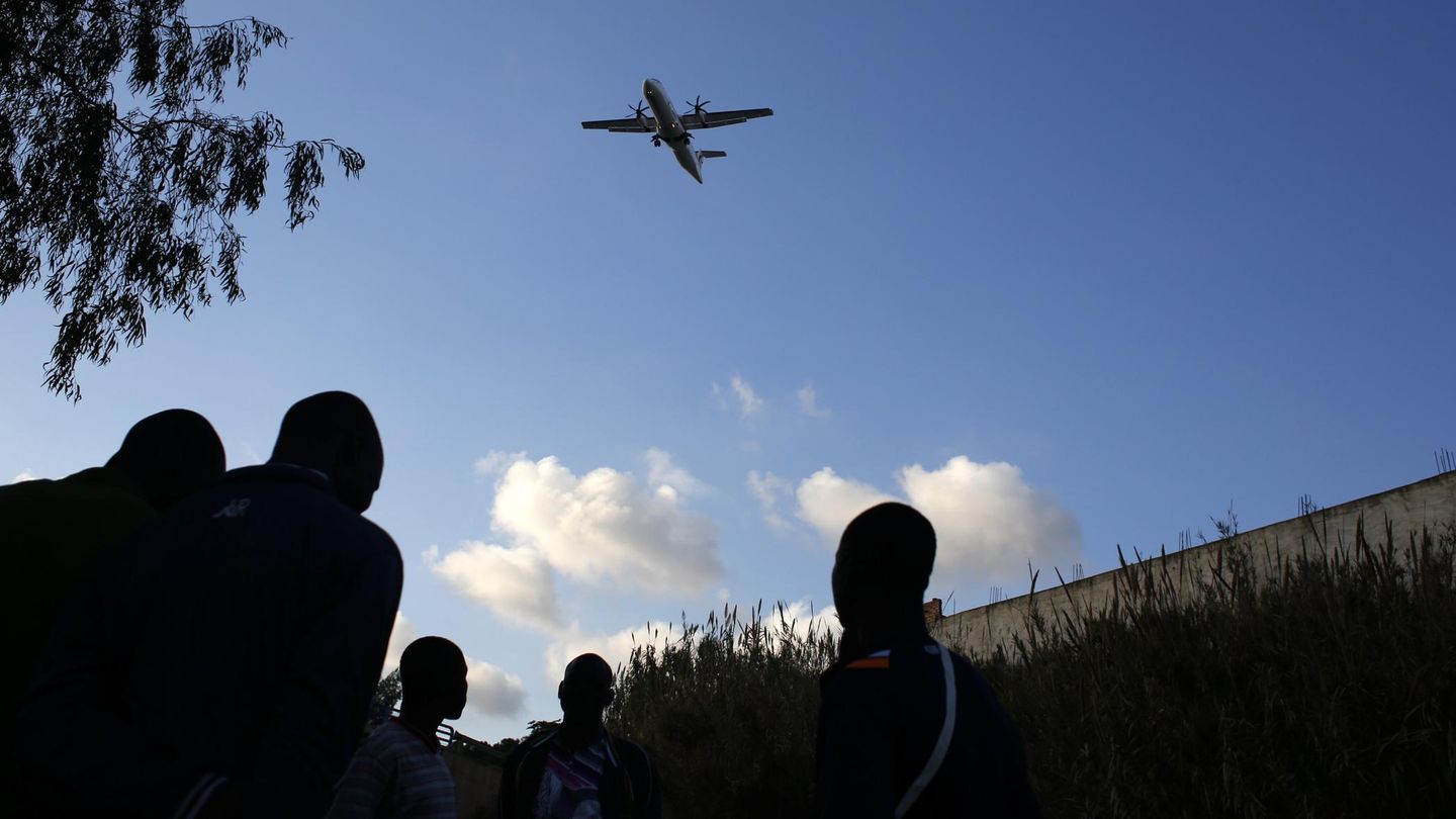 Un grupo de inmigrantes observa un avión que parte de Melilla (Reuters).