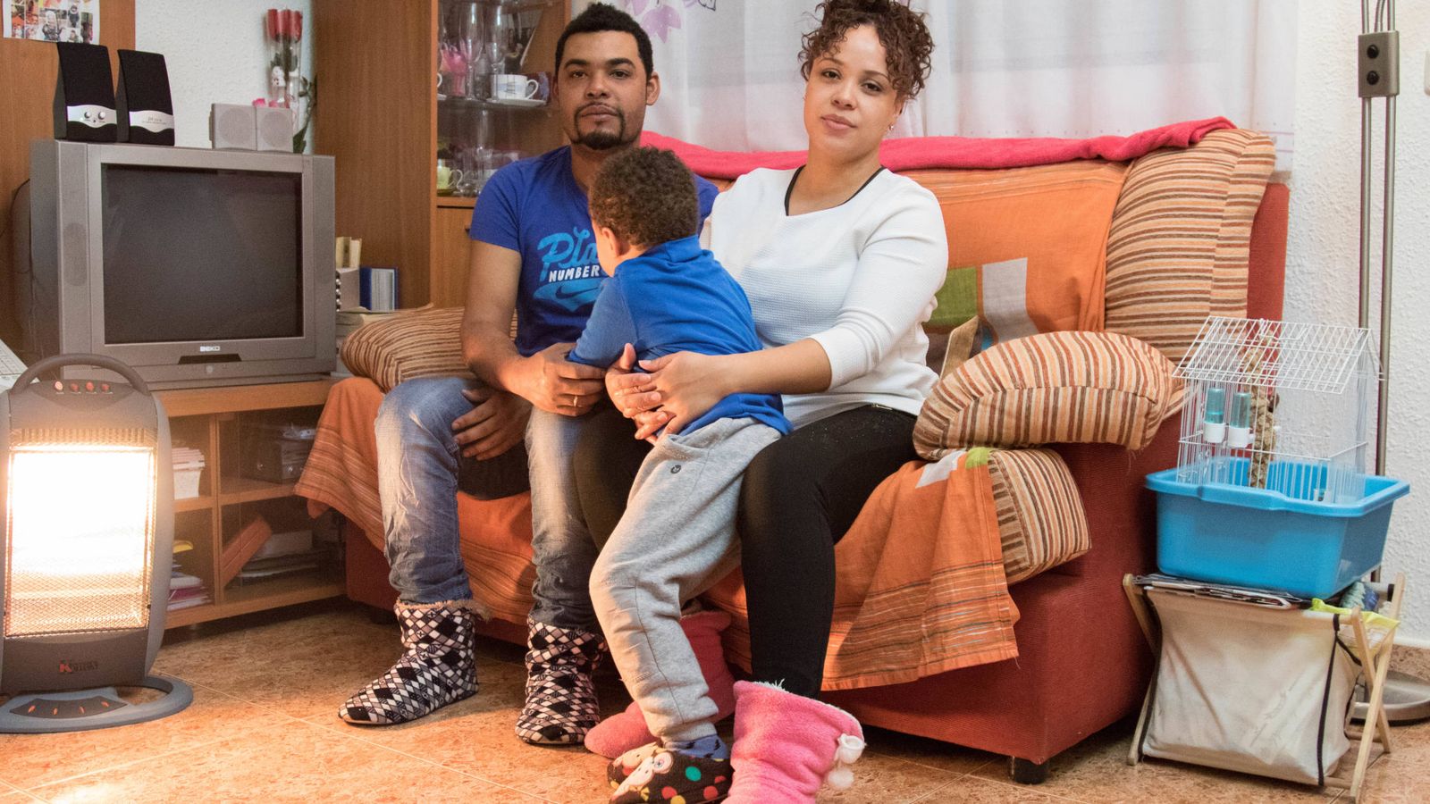 Foto: Carlos y Carine posan junto a su hijo en su salón. Los dos trabajan pero no llegan a pagar el alquiler. (D. B.)