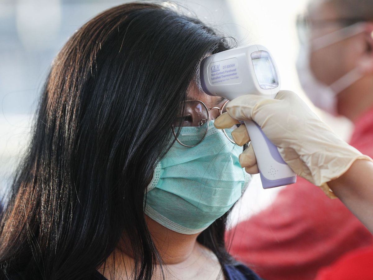 Foto: Un operario toma la temperatura corporal de una mujer en Singapur. (Reuters)