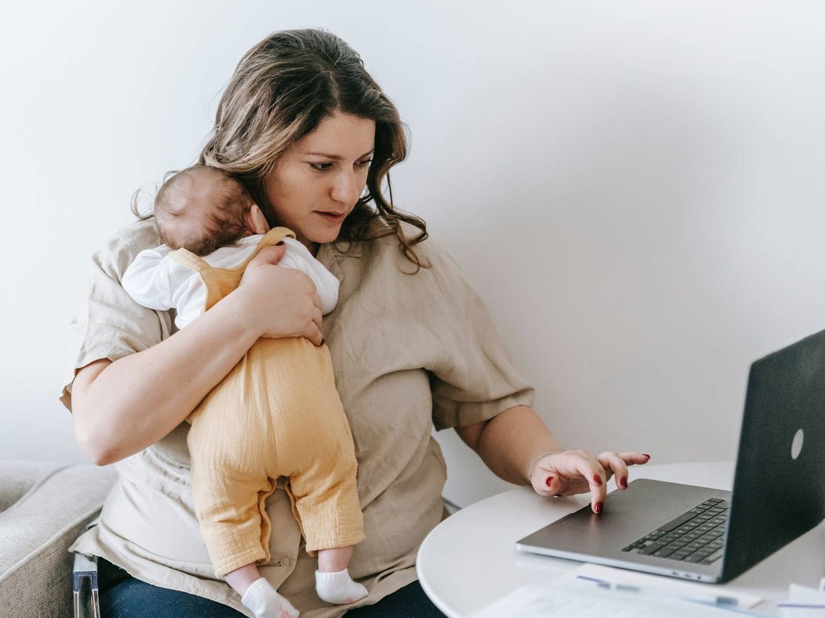 Foto: Una madre escribe en su ordenador con su bebé en brazos. (Pexels/Sarah Chai)