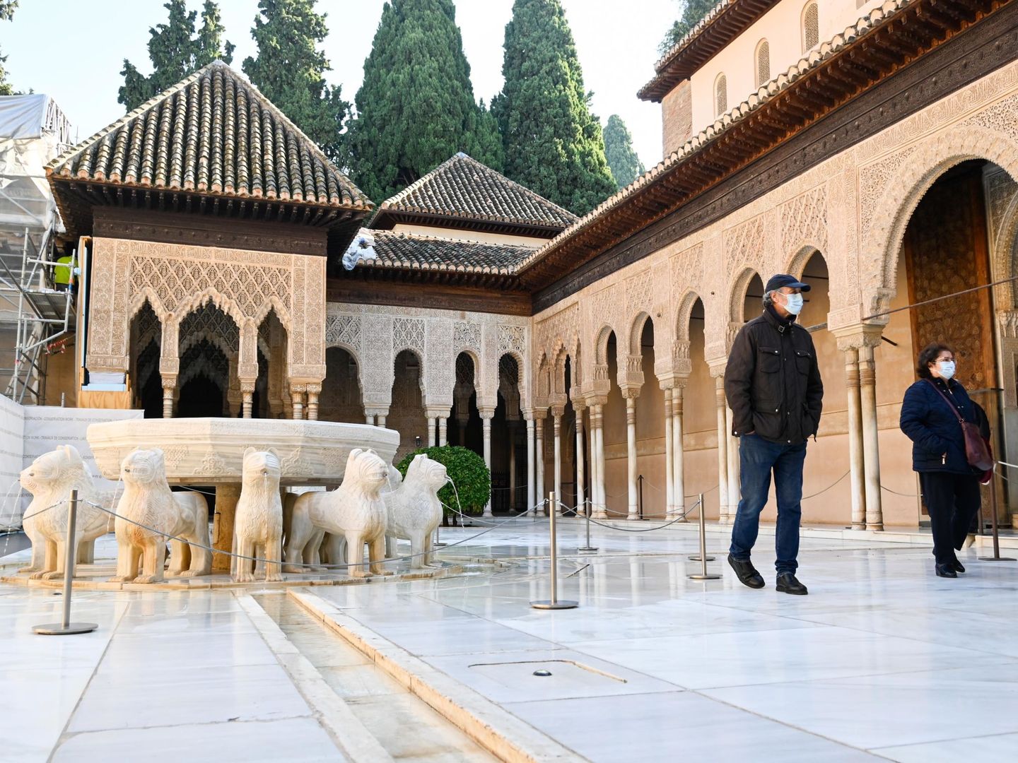Dos visitantes, ayer, por el Patio de Leones de la Alhambra de Granada.
