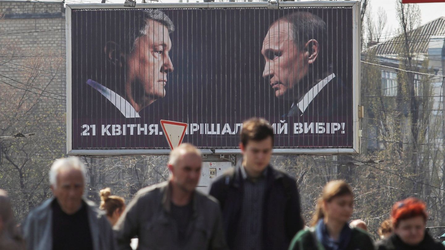 Viandantes caminan junto a un cartel electoral en el que aparecen Petro Poroshenko (i), ante el presidente ruso, Vladímir Putin (d). 