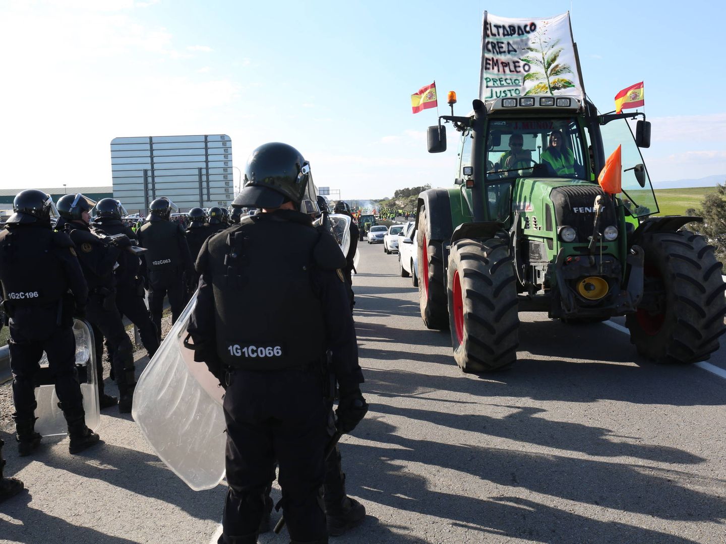 Un tractor pasa junto a unidad de antidisturbios de la Policía Nacional en la A-5. (D. B.)