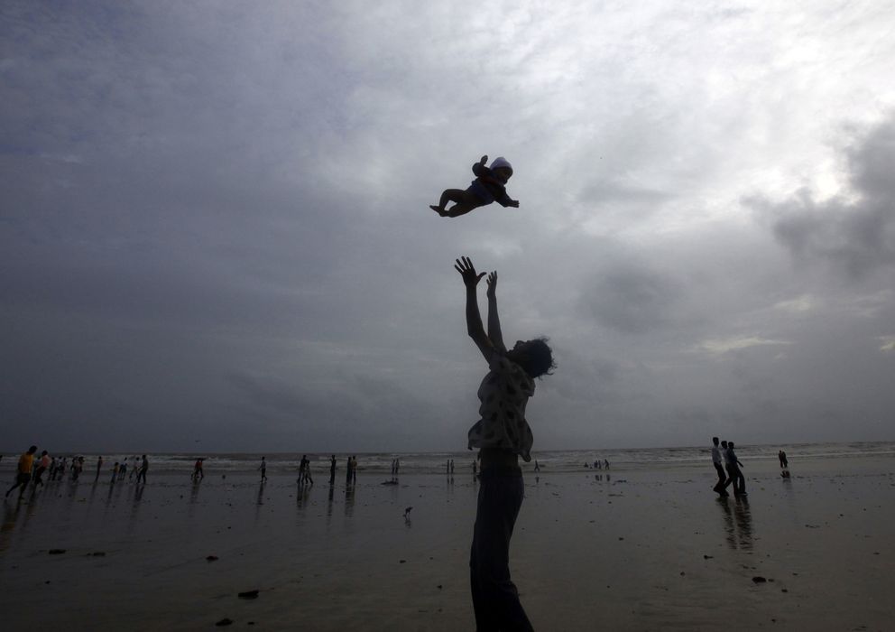 Foto: Un padre juega con su bebé durante el monzón en una playa de Mumbai (Reuters). 