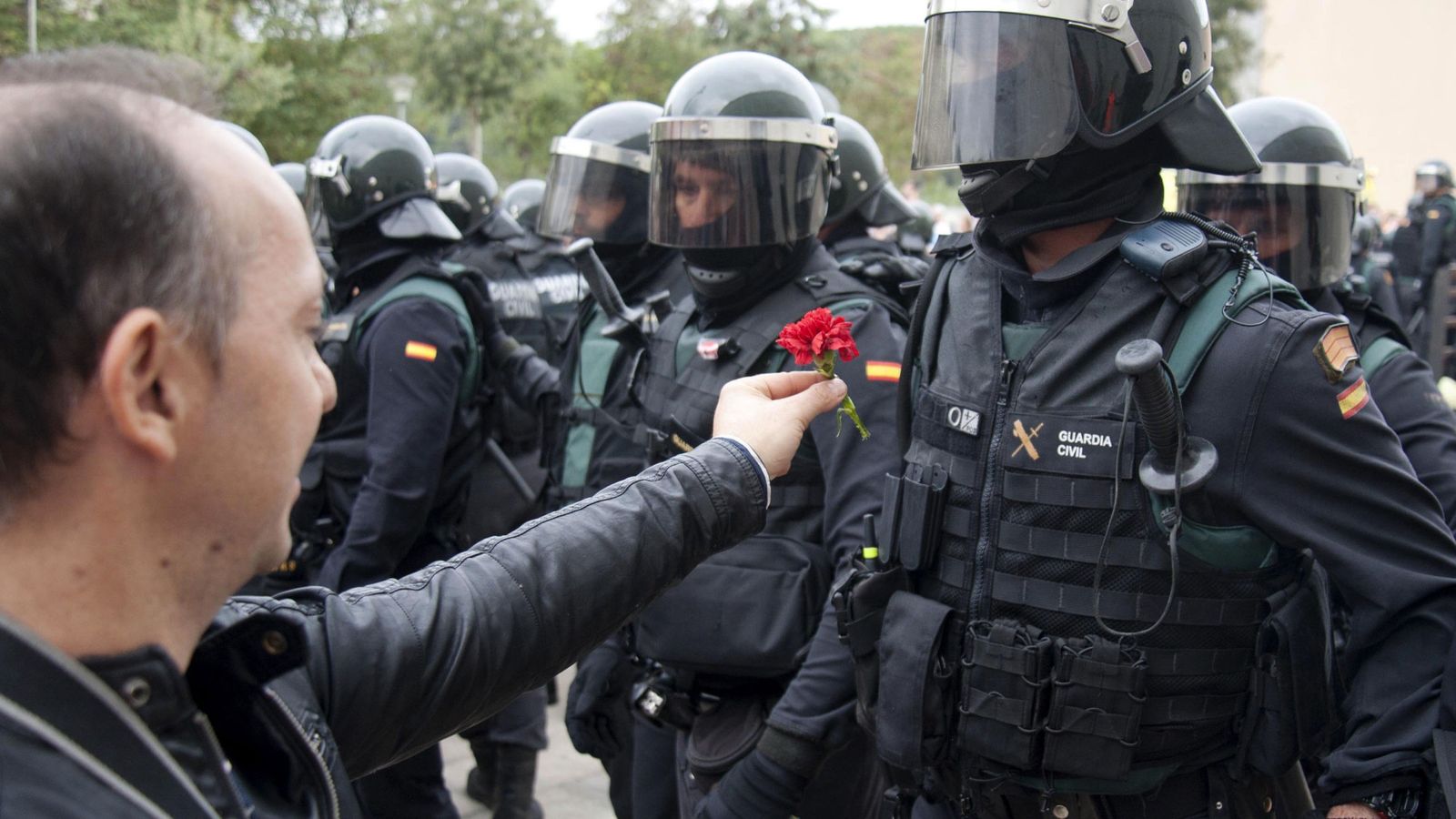 Foto: Un hombre ofrece un clavel a un agente de la Guardia Civil en el centro de votación de Sant Julià de Ramis (Girona). (EFE)