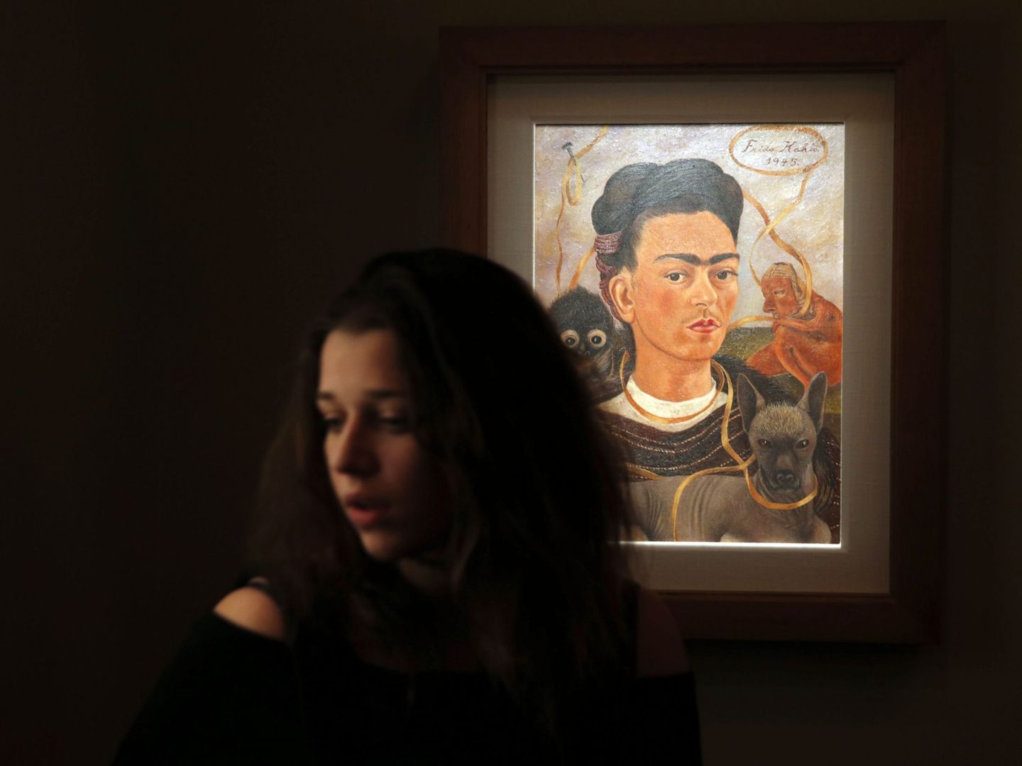 Una mujer, ante la obra 'Autorretrato con mono', de Frida Kahlo. (EFE)