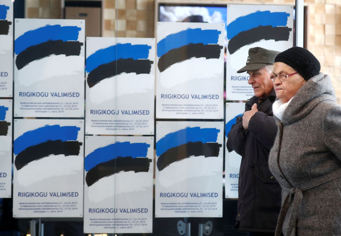 Dos personas pasan frente a unos carteles electorales en Parnu, Estonia, el 3 de marzo de 2019. (Reuters)