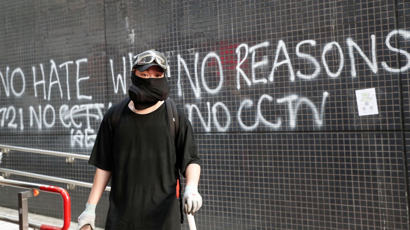 Un manifestante posa frente a un grafiti en Hong Kong. (Reuters)