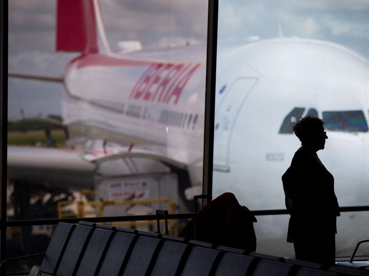 Foto: Una pasajera observa un avión de Iberia estacionado en un aeropuerto. (EFE)