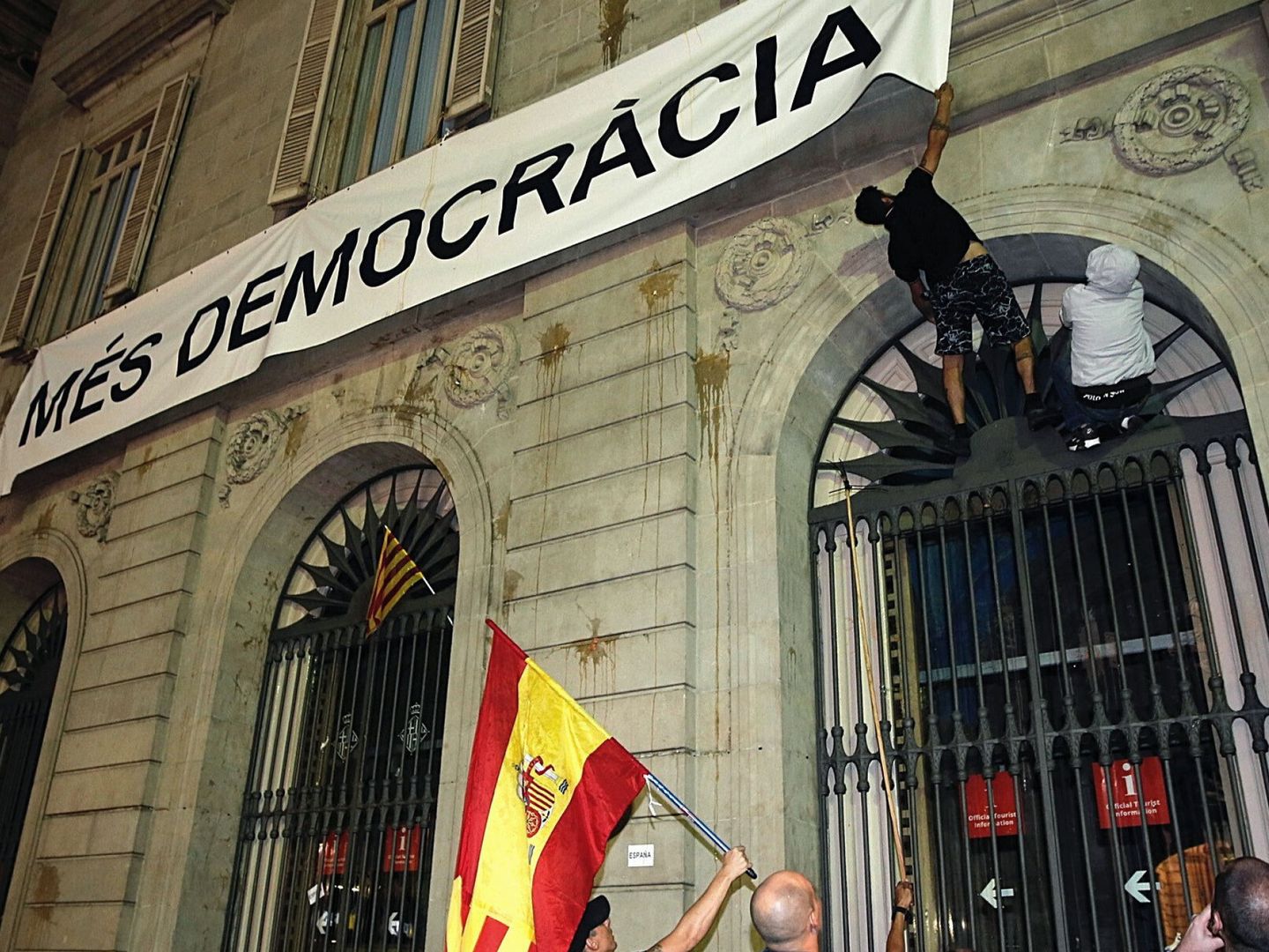 Dos personas intentan arrancar la pancarta colgada en el ayuntamiento de Barcelona. (EFE)