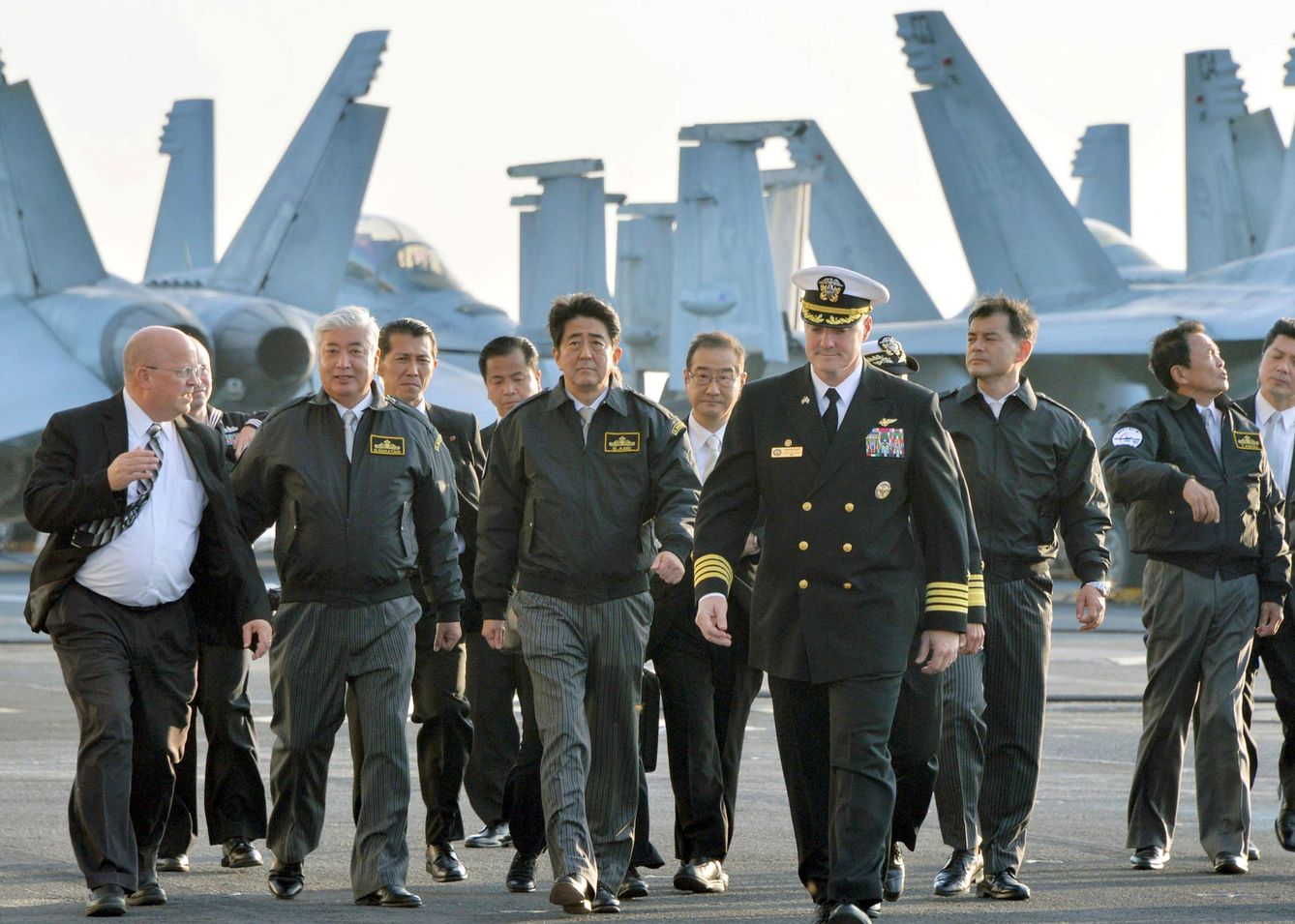 Shinzo Abe (c), primer ministro de Japón, junto al responsable de Defensa nipón (2i) y el capitán del USS Ronald Reagan en la bahía de Sagami, en 2015. (Reuters)