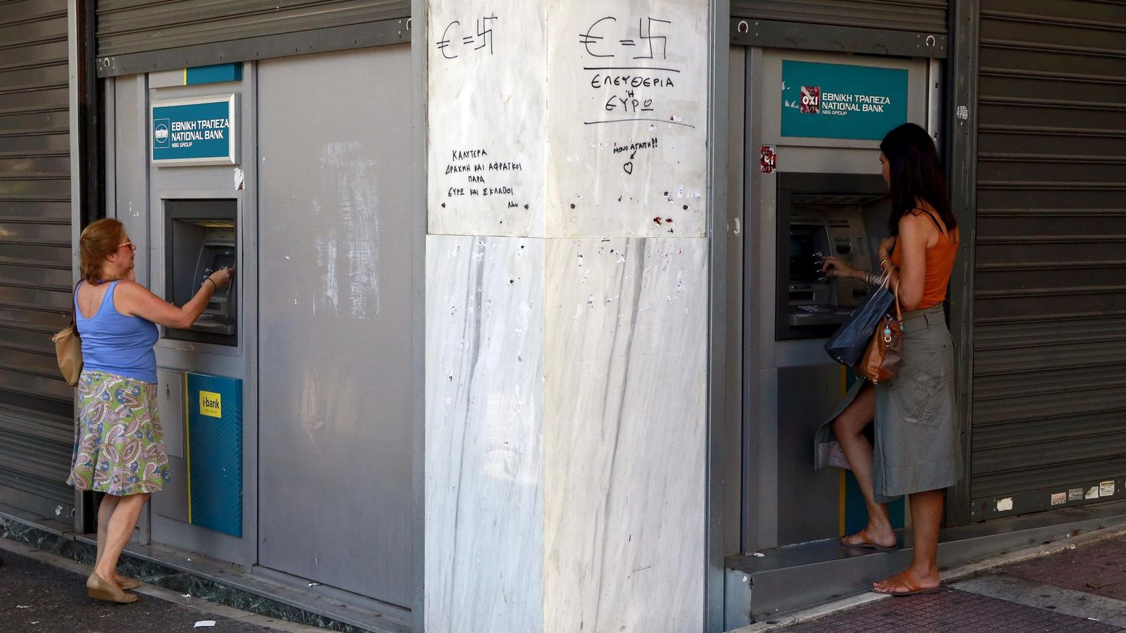 Foto: Dos mujeres sacan dinero en los cajeros de un banco griego. (Reuters)