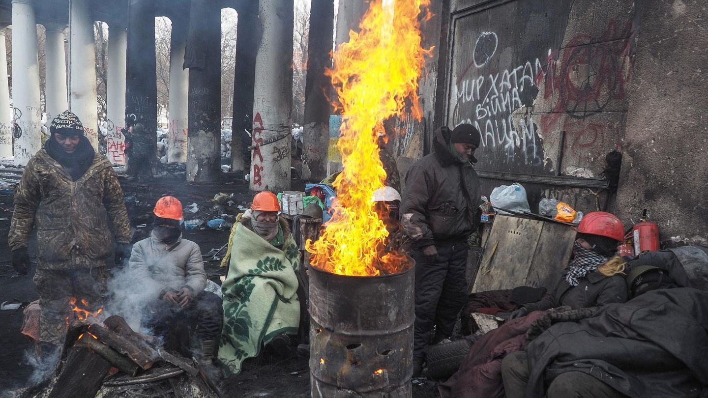Manifestantes antigubernamentales descansan junto al fuego en Kiev (Reuters).