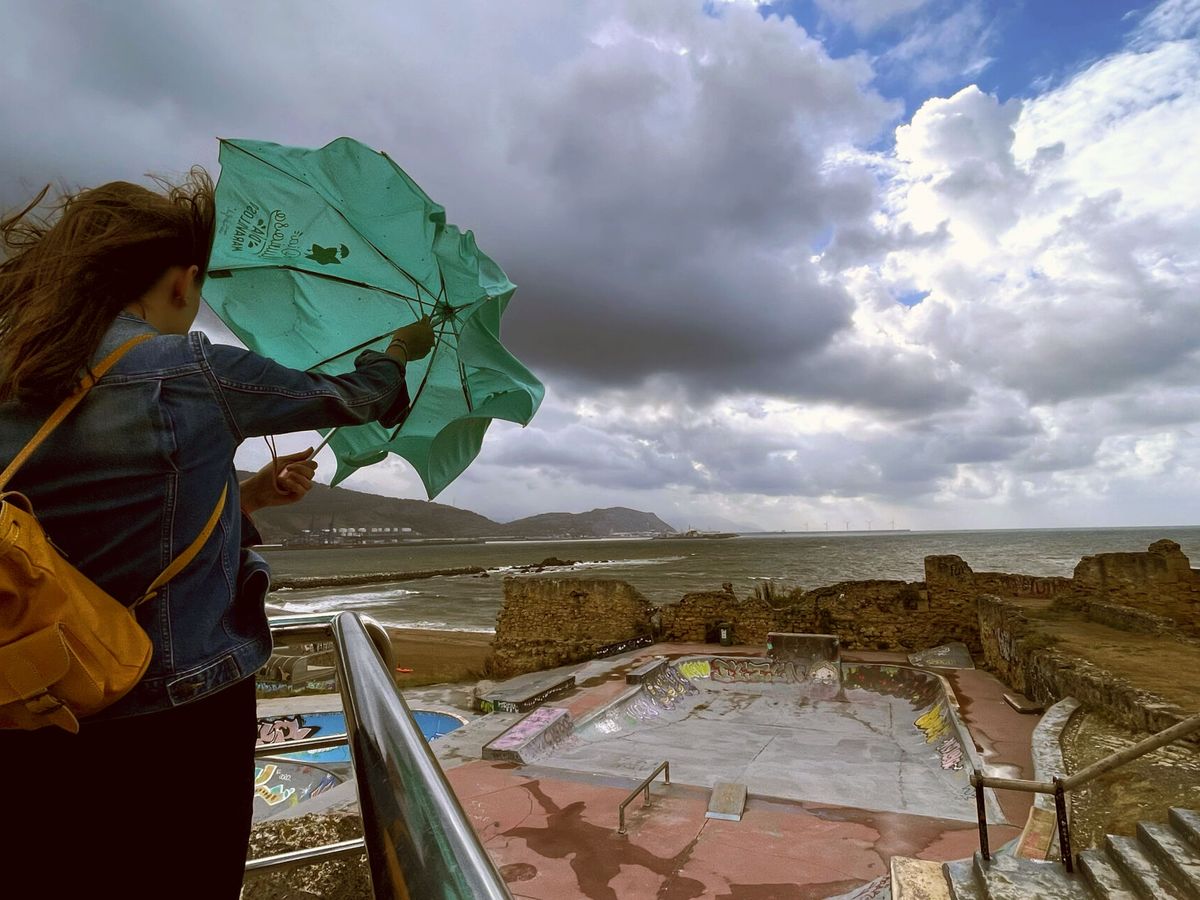 Foto: Una mujer trata de abrir su paraguas. (EFE/Miguel Toña)