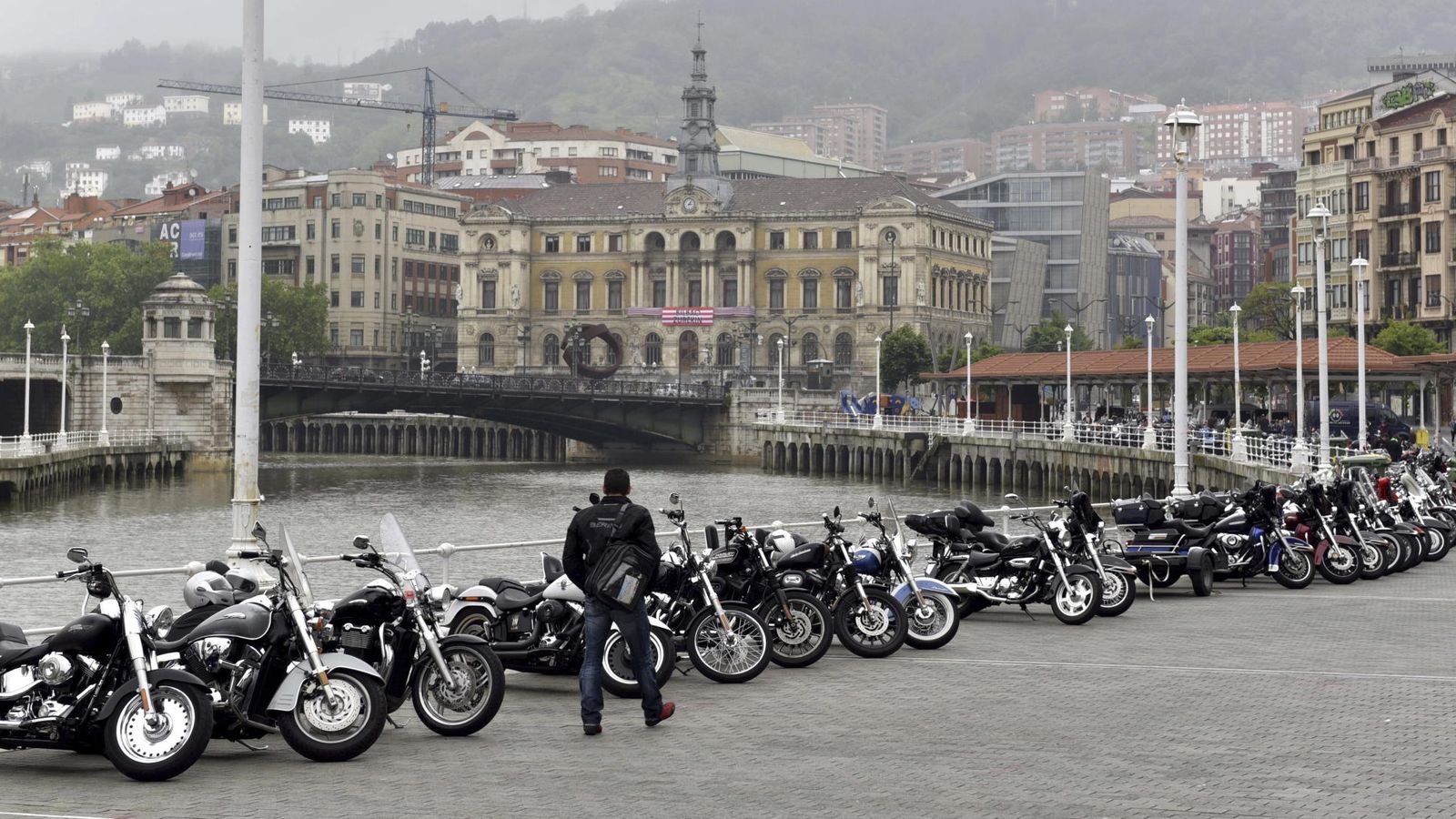 Foto:  Un hombre pasa ante unas Harley Davidson aparcadas en el Arenal de Bilbao. (EFE)
