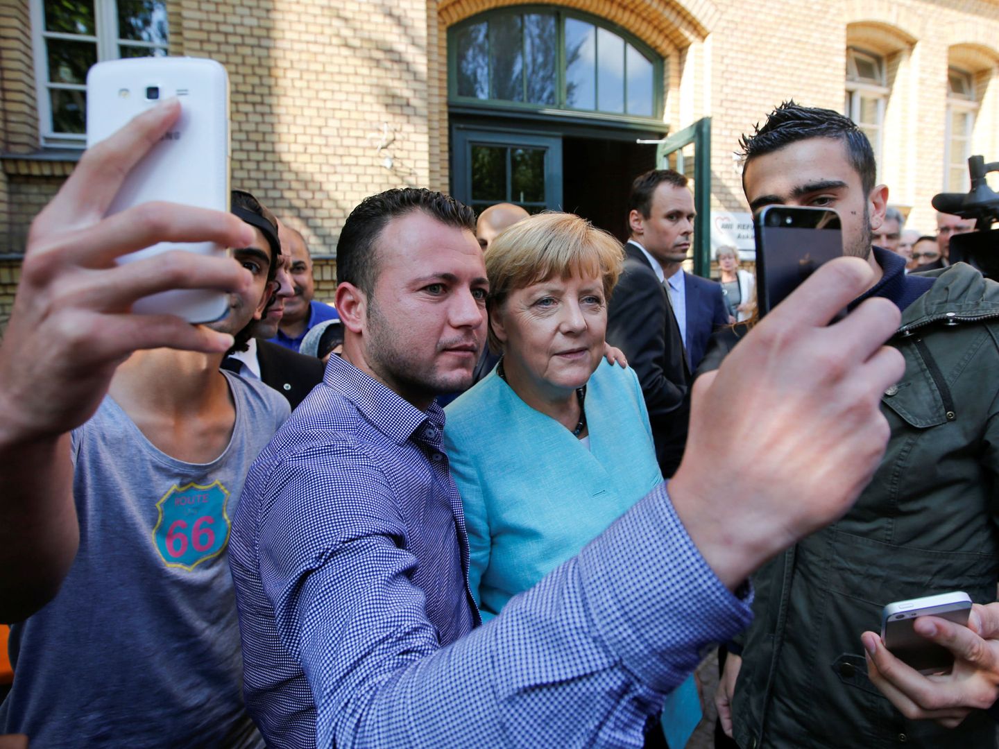 Merkel se fotografía con un grupo de refugiados a la salida de un centro de acogida. (Reuters)