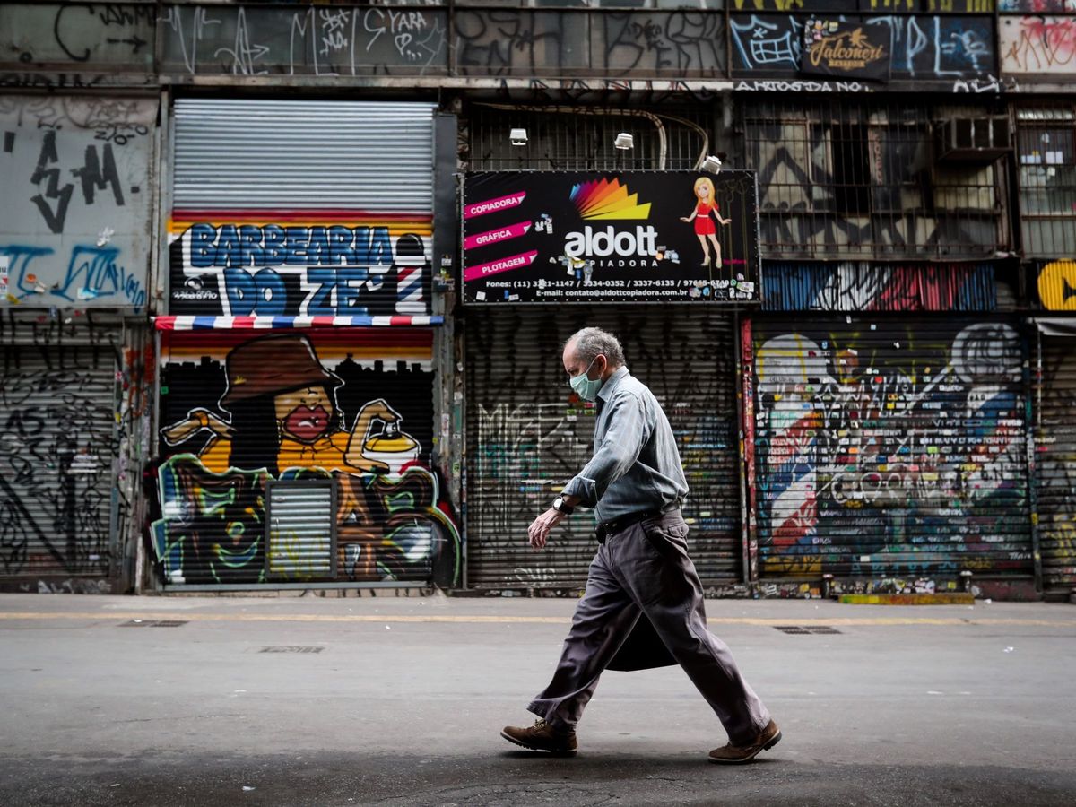 Foto: Un hombre camina frente a locales comerciales cerrados este miércoles, en Sao Paulo (Brasil).  