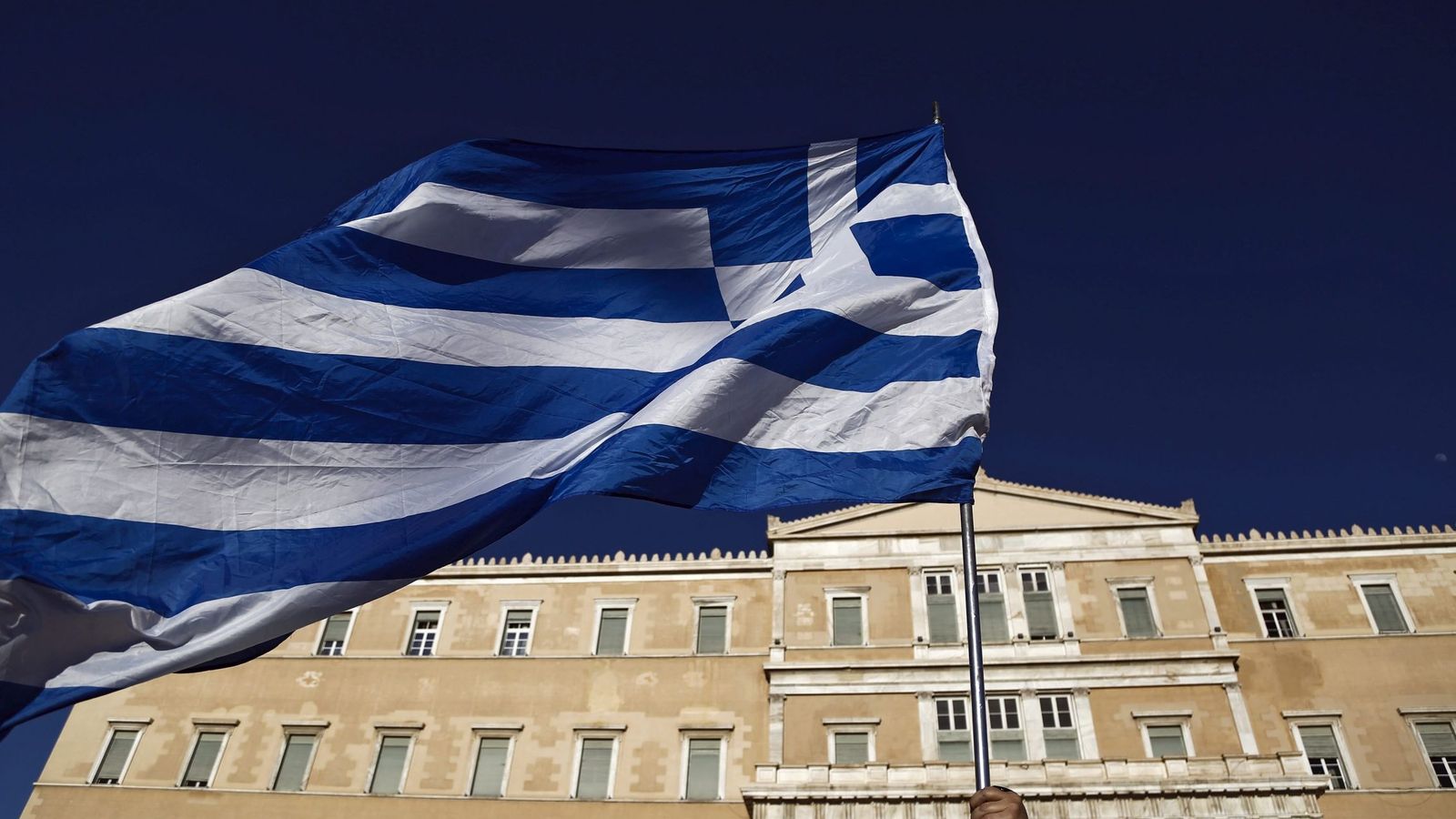 Foto: Un manifestante ondea una bandera griega durante una protesta contra el gobierno en el exterior del Parlamento de Atenas, en Grecia. (EFE)