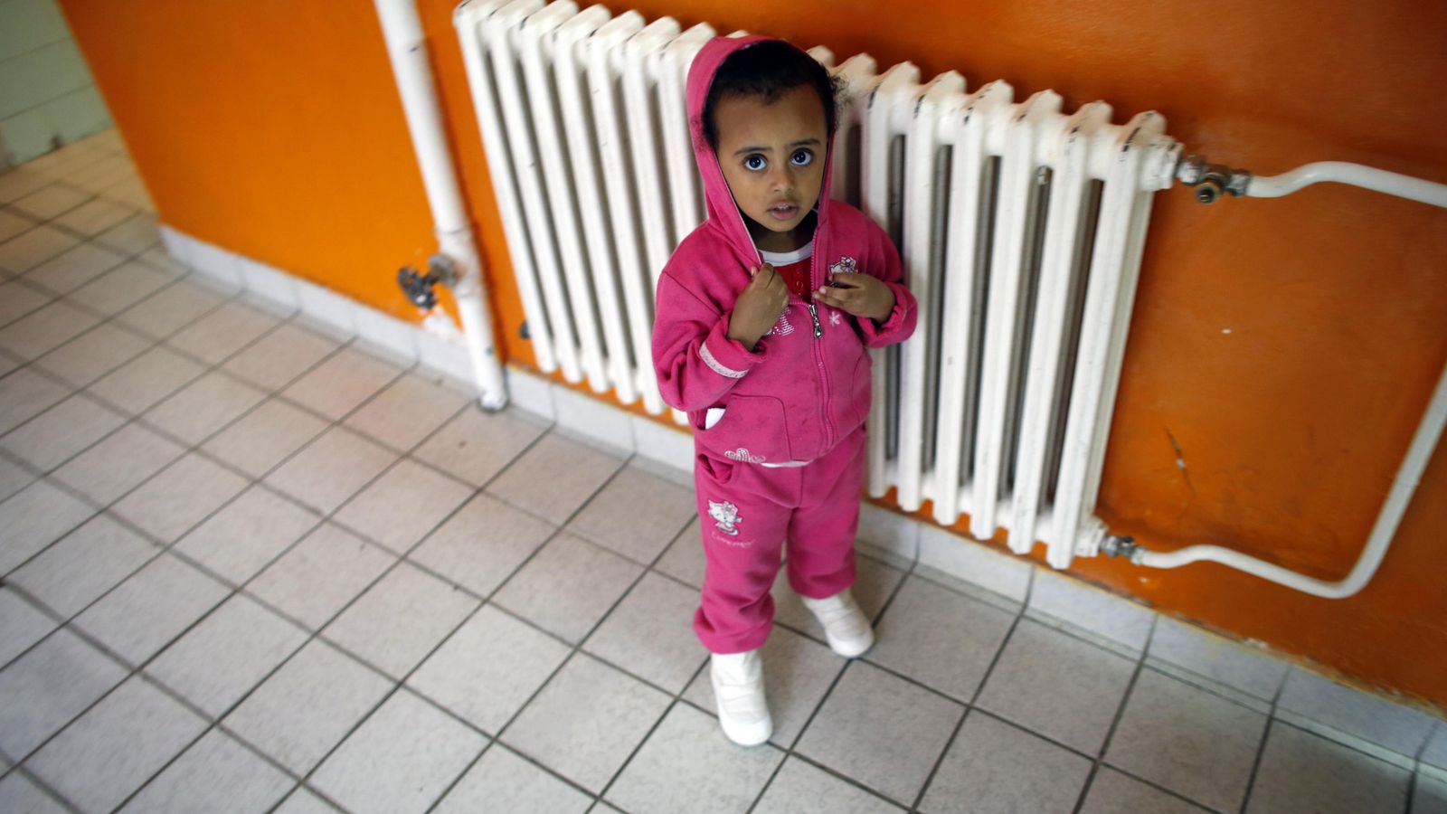 Foto: Una niña se calienta junto a un radiador. (REUTERS)