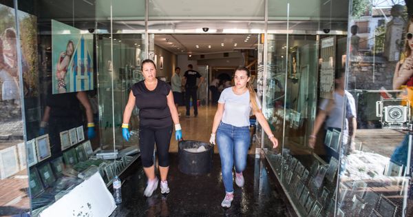 Foto: Dos empleadas de una tienda de fotografía retiran granizo del interior. (D. B.)