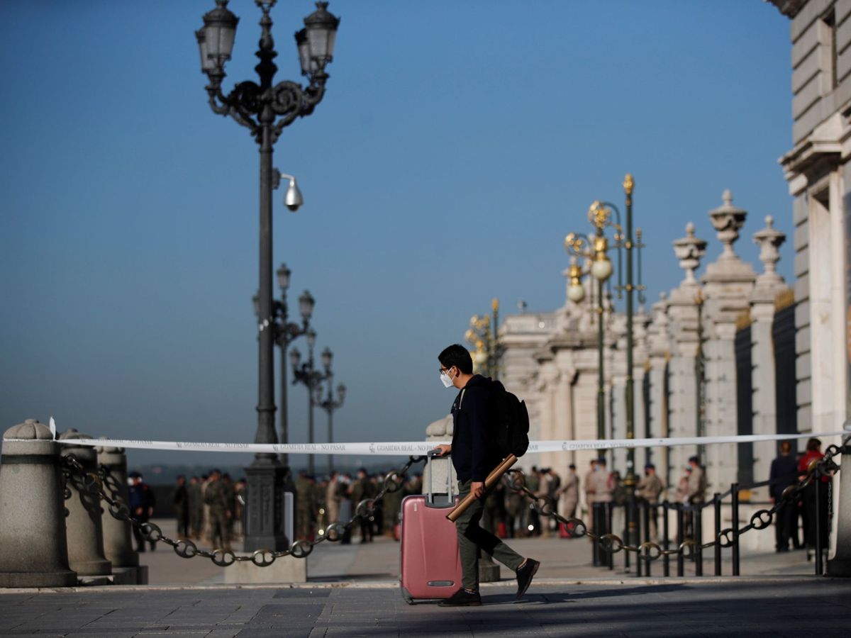 Foto: Un joven con su maleta pasa ante el Palacio Real de Madrid. (EFE) 