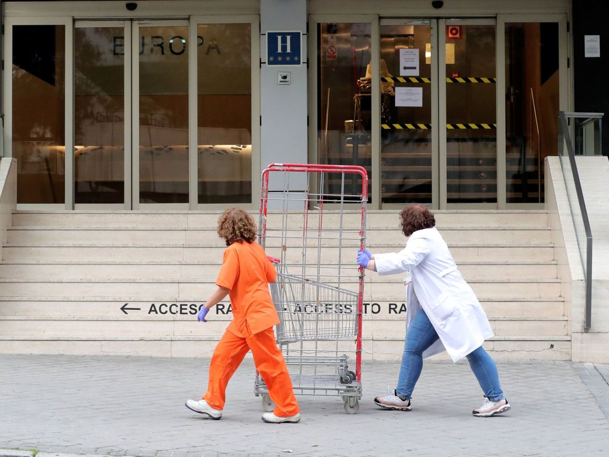 Foto: Dos empleadas con máscaras sanitarias pasan frente al Gran Hotel Colon. (EFE)