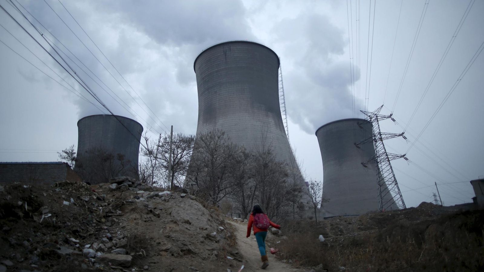 Foto: Una chica camina junto a las torres de refrigeración en Shijiazhuang. (Reuters)