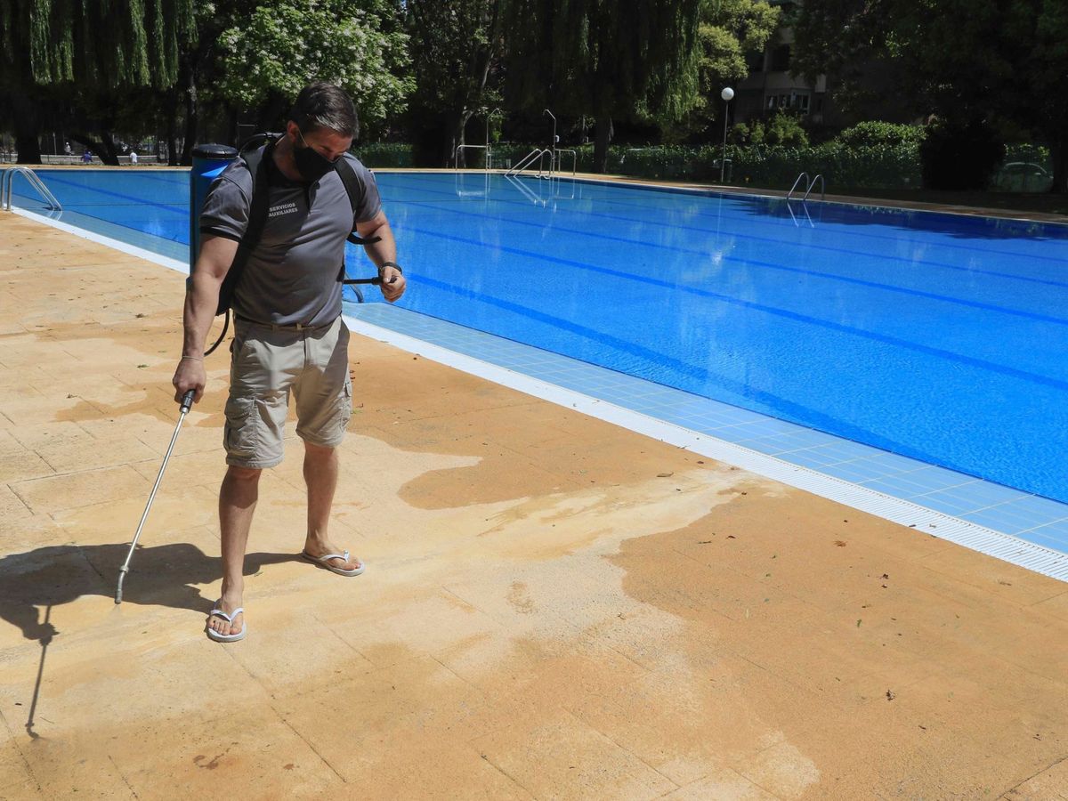 Foto: Un operario desinfecta el perímetro de una piscina en Madrid. (EFE)