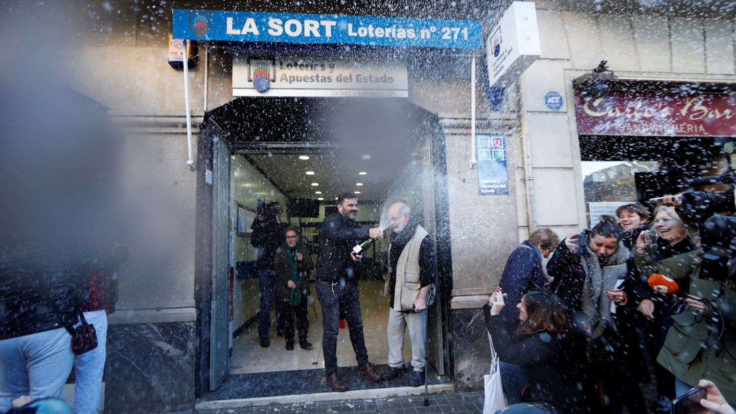 El dueño de la administración de lotería de la calle Travessera de Gràcia muestra su alelgría tras haber vendido integramente el primer premio del sorteo extraordinario de El Niño (EFE)