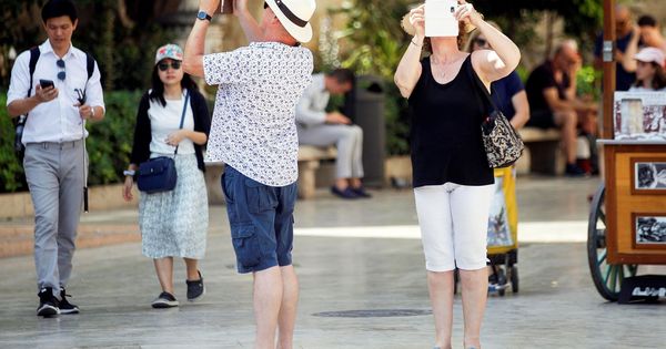Foto: Dos turistas consultan su teléfono móvil en la Comunidad Valenciana. (EFE)