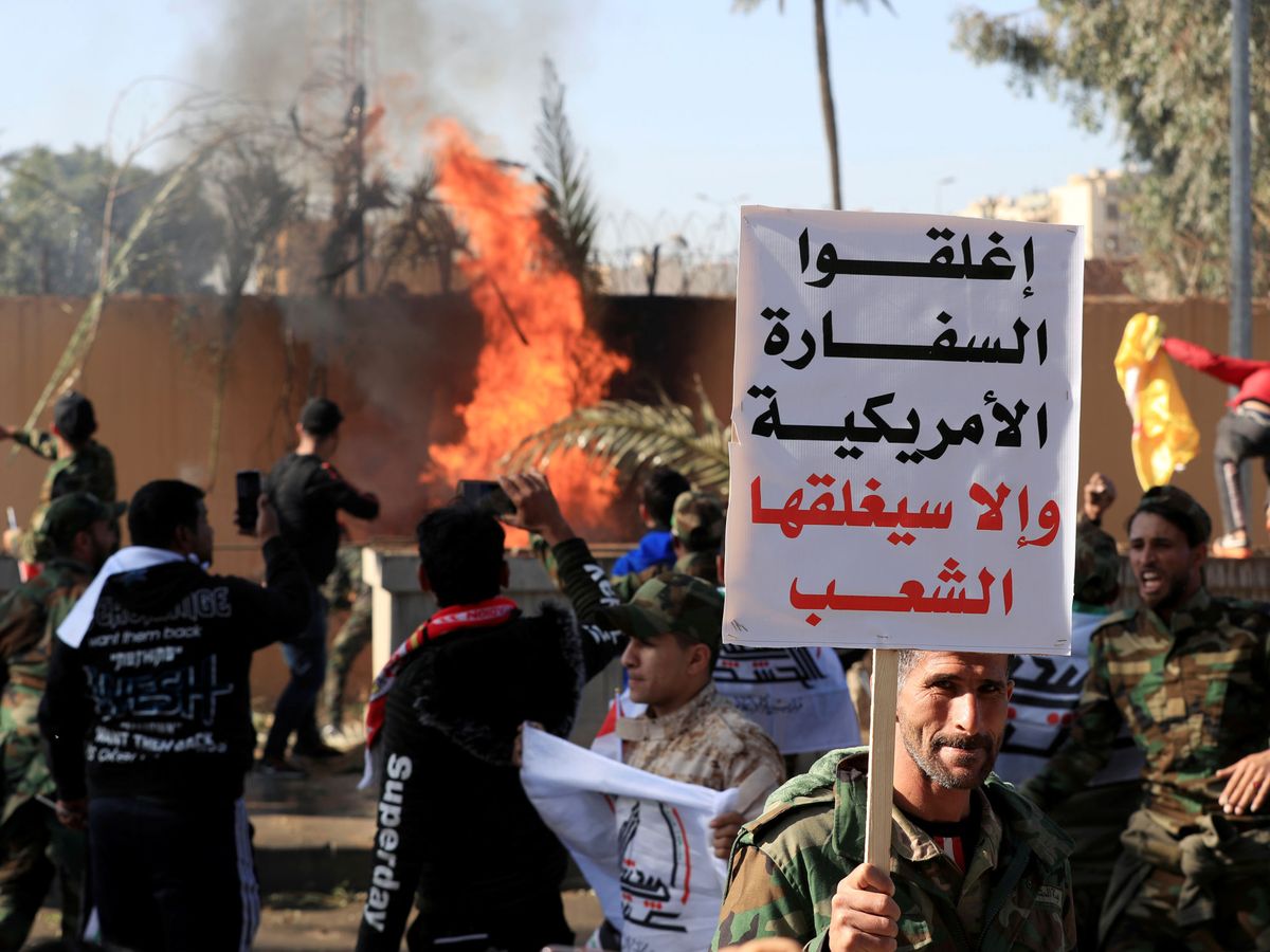 Foto: Asaltantes en la Embajada estadounidense en Bagdad. El cartel reza: "Cerrad la embajada estadounidense o la gente la cerrará". (Reuters)