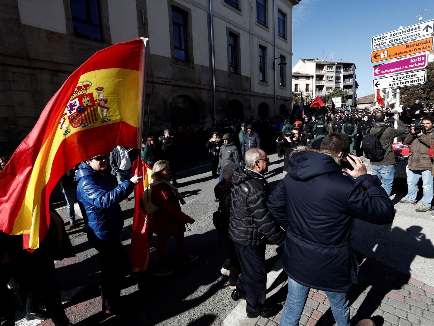 Varias personas se dirigen con banderas nacionales al acto de España Ciudadana en Alsasua entre el cordón policial. (EFE)