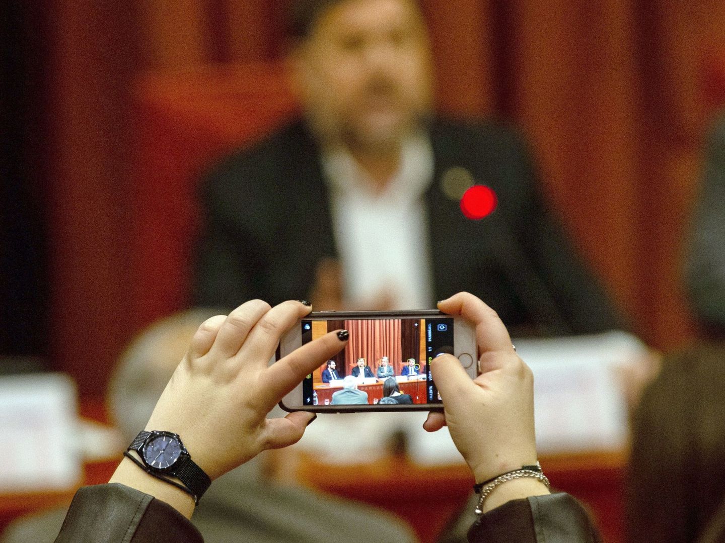 Una mujer fotografía a Junqueras, durante su comparecencia en el Parlament. (EFE)