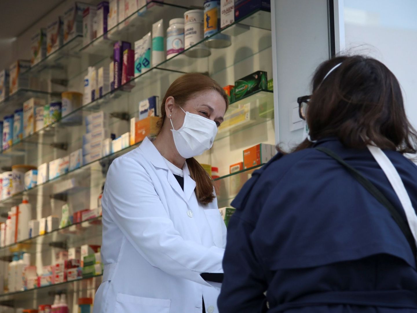 Una clienta conversa con una empleada a las puertas de una farmacia del centro de Madrid (EFE)