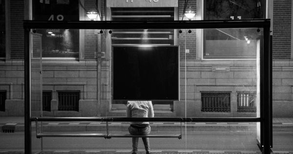 Foto: Una mujer espera el autobús sentada en una marquesina. 